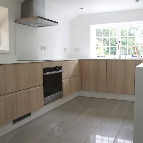 kitchen with white worktops and acacia oak panels